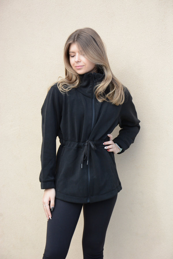 Woman wearing a Women's High Neck Athleisure Jacket in black, featuring a stylish design with a drawstring waist.
