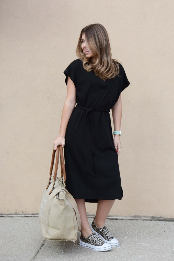 Lillie's Black V-Neck Athleisure Dress worn by a model with a stylish bag and sneakers, showcasing a relaxed, polished look.